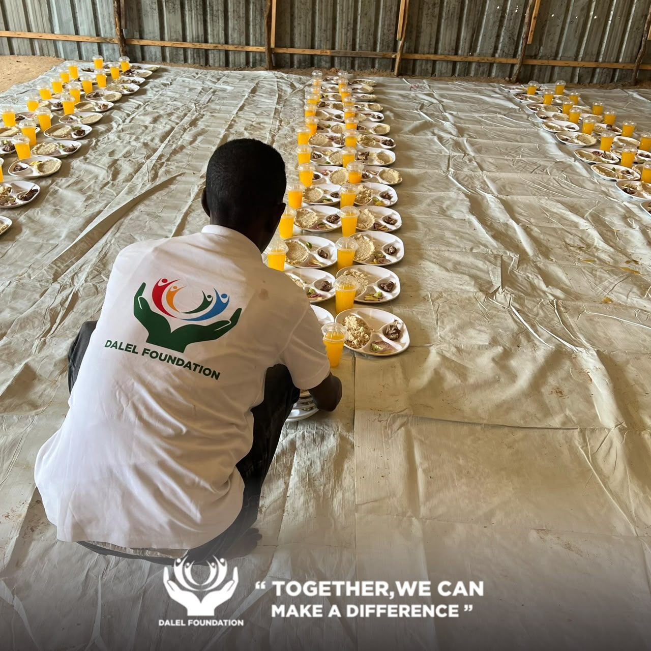 A Dalel Foundation volunteer laying out rows of hot meals and drinks before a community food distribution